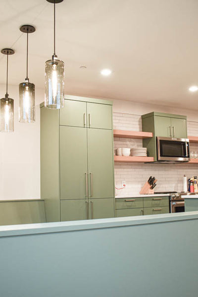 Interior design of kitchen with light sage colored cabinets and wood floating shelves. Designed by interior designer Erica LeMaster Sargent. 