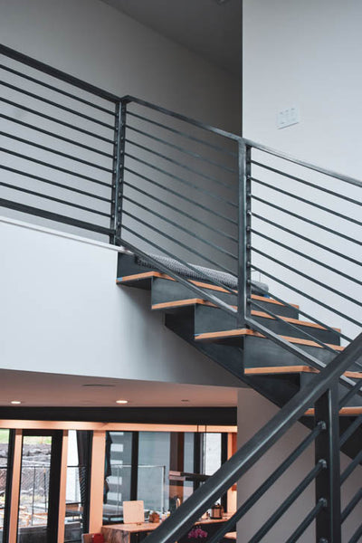 Interior design of floating staircase with wood steps and black metal railing. Designed by interior designer Erica LeMaster Sargent. 