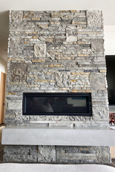 Interior design of custom fireplace surrounded by stone pillar with concrete floating shelf. Designed by interior designer Erica LeMaster Sargent. 