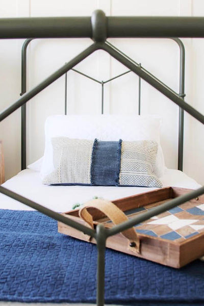 Interior design of black metal framed bed with natural wood and blue accents. Designed by interior designer Erica LeMaster Sargent. 