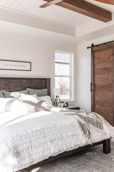 Interior design of guest bedroom with wood ceiling beams and wood barn door to bathroom. Designed by interior designer Erica LeMaster Sargent. 