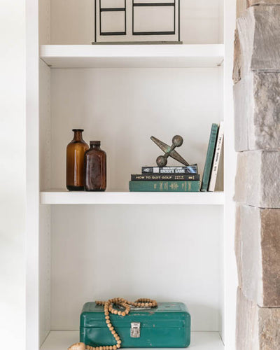 Interior design of shelves with teal accents. Designed by interior designer Erica LeMaster Sargent. 