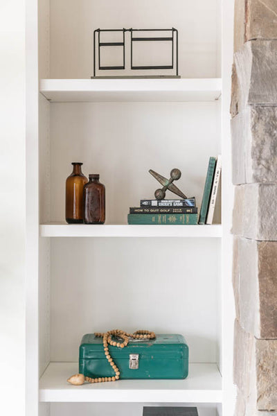 Interior design of shelves with teal accents. Designed by interior designer Erica LeMaster Sargent. 